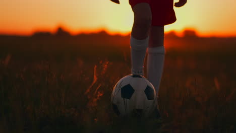 A-little-boy-runs-across-the-field-at-sunset-with-a-soccer-ball.-Dribbling-with-the-ball